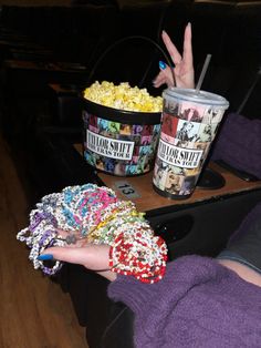 a person holding their hand up in front of two buckets of popcorn