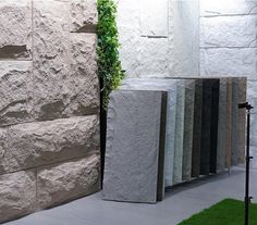 several different types of stone on display in front of a white brick wall and green grass