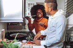 a man and woman standing in front of a stove with food on the burners