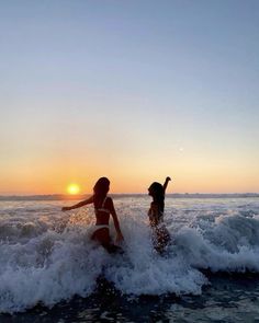 two people in the ocean at sunset with one person on surfboard and another standing up