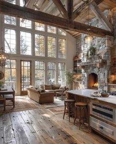 an open concept kitchen and living room with stone fireplace, wood flooring and large windows