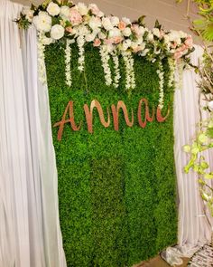 an arrangement of flowers and greenery is displayed in front of a backdrop with the word anna