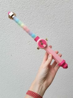 a hand holding a pink and blue toothbrush