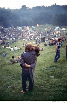 two people hugging each other in front of a large crowd at an outdoor concert or festival