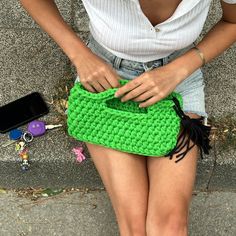 a woman is holding a green crocheted purse