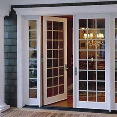 the front door to a house with glass doors and chandelier hanging from it's side