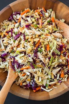 a wooden bowl filled with coleslaw and carrots next to a wooden spoon