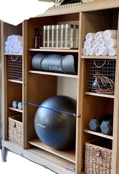 an exercise ball is sitting on top of a gym ball in a wooden cabinet with baskets