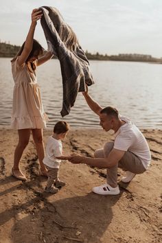 a man, woman and child are on the beach with a towel over their heads