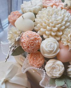 an arrangement of flowers is displayed on a table top with white and peach colors in the center