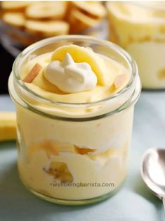 a glass jar filled with dessert sitting on top of a table next to two spoons