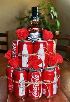 a stack of coca - cola cans with roses tied around them on a wooden table