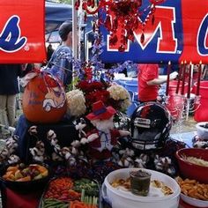 a table full of food and decorations at a football game with fans in the background