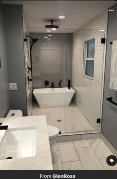 a bathroom with a glass shower door and white tub in the corner, along with two sinks