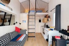 a loft bed with a ladder in the middle of it and a kitchen area next to it