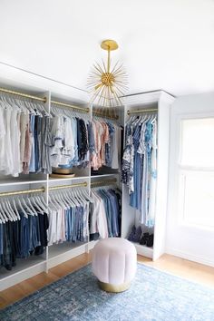 a walk in closet with clothes on hangers and a rug underneath the chandelier