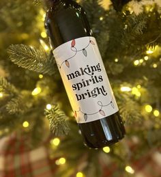 a bottle of wine is hanging from a christmas tree with lights on it and the words making spirits bright