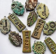 several different types of metal tags with words on them and leaves in the middle one