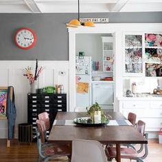 a dining room table with chairs and a clock on the wall