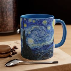 a blue coffee mug sitting on top of a wooden cutting board next to a cookie