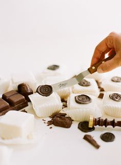 a person cutting up some white chocolates with a large knife on top of them