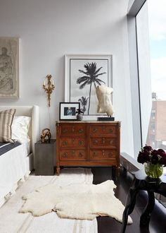 a bedroom with a bed, dresser and pictures hanging on the wall next to it