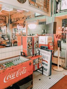 an old coke machine is in the middle of a diner's counter and there are signs on the wall