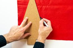 a man is making a christmas tree out of cardboard and glues it on the wall