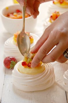 a person is spooning some fruit into a dessert