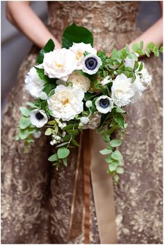 the bride's bouquet is adorned with white flowers and greenery, while her dress was gold