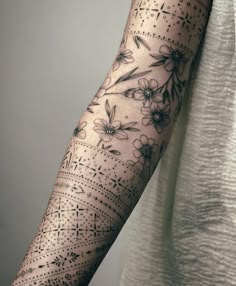 a woman's arm with flowers and dots on the side of her arm,