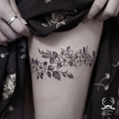 a close up of a woman's thigh with flowers and leaves on the side