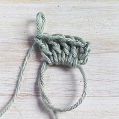 a close up of a piece of yarn on a wooden surface with the end knoted together