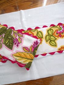 two white napkins with colorful floral designs on them sitting on a wooden table top