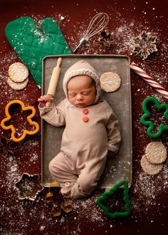 a baby is laying in a pan with cookies and pretzels