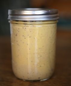 a jar filled with mustard sitting on top of a wooden table