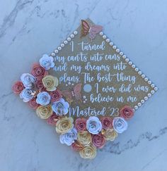 a graduation cap decorated with paper flowers on a white marble surface, that says i turned my cuts into caps and my dreams into long ago the best things i ever had to do