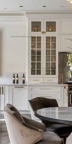 an elegant kitchen with white cabinets and marble dining room table surrounded by gray velvet chairs