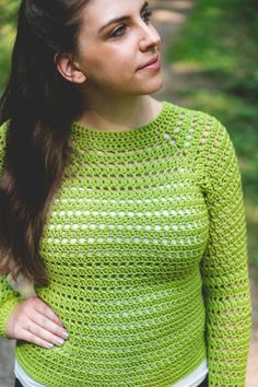 a woman wearing a green crochet sweater with her hair pulled back and looking off to the side