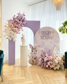 a room with purple and white flowers on the floor, two vases in front of a sign that says precious bunny