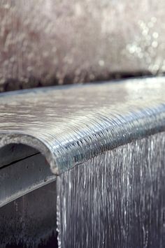 the back end of a metal bench with water running down it's sides,