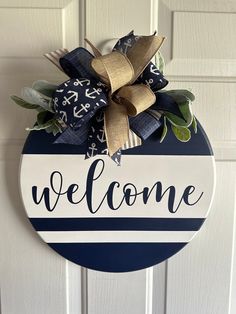 a blue and white welcome sign hanging on the front door with gold ribbon around it