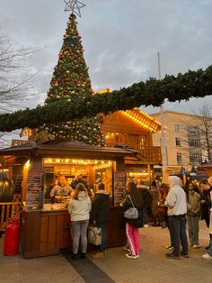 people standing in front of a food stand with a christmas tree on top