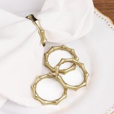 two golden metal objects sitting on top of a white plate next to a napkin holder