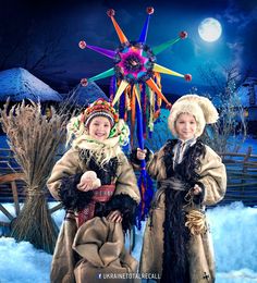 two young children dressed in costumes standing next to each other on snow covered ground at night