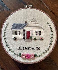 a white embroidered wall hanging with a house on it