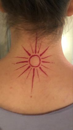 a woman's neck with a tattoo on it that looks like the sun is shining