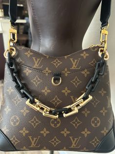 a brown and black purse with gold chains hanging from it's front pocket on a mannequin