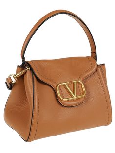 ALLTIME BY VALENTINO GARAVANI handle bag. Made of soft grained calfskin. Internal magnetic closure; comfortable main compartment and internal pocket closed by zip; metal feet. Two shoulder straps: adjustable and removable ribbon shoulder strap and adjustable and removable leather shoulder strap. Featuring a gold-tone metal VLogo. Valentino Top, Mens Designer Shoes, Brown Bag, Marine Serre, Brown Bags, Sneaker Wedge, Luxury Accessories, Handle Bag, Italian Fashion