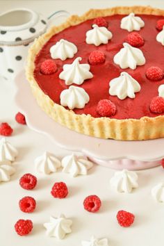 a pie with raspberries and whipped cream on top